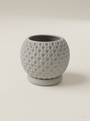 Vaso Bubble tondo coperto da piccole conche rotonde come bolle, con sottovaso, stampato in 3D in PLA grigio chiaro.