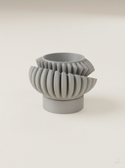 Vaso Luxira con alette radiali su due giri e sottovaso cilindrico, stampato in 3D in PLA grigio chiaro.