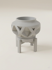 Vaso Nomio con grandi fasce in rilievo incrociate a X, con sottovaso e supporto a quattro gambe, stampato in 3D in PLA grigio chiaro.